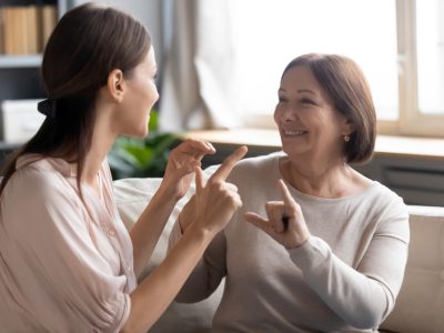 Close,Up,Smiling,Mature,Mother,And,Grownup,Daughter,Speaking,Sign