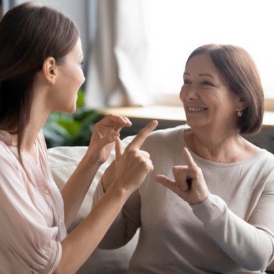 Close,Up,Smiling,Mature,Mother,And,Grownup,Daughter,Speaking,Sign